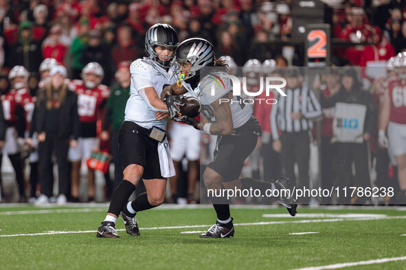 Oregon quarterback Dillon Gabriel #8 hands the ball off to Oregon running back Jordan James #20 against the Wisconsin Badgers at Camp Randal...