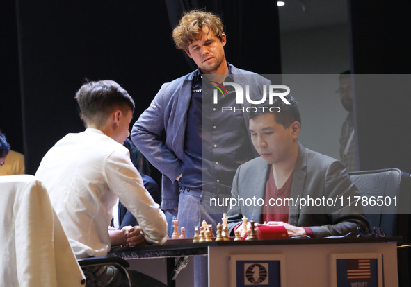 Norway's Magnus Carlsen stands with Daniil Dubov (left) and Wesley So (right) after he wins the match against India's Vidit Gujrathi on the...