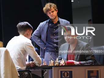 Norway's Magnus Carlsen stands with Daniil Dubov (left) and Wesley So (right) after he wins the match against India's Vidit Gujrathi on the...