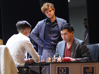 Norway's Magnus Carlsen stands with Daniil Dubov (left) and Wesley So (right) after he wins the match against India's Vidit Gujrathi on the...