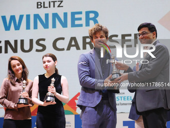 Norway's Magnus Carlsen, a chess grandmaster and five-time World Chess Champion, receives the winner's trophy from Indian chess grandmaster...