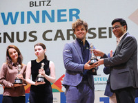 Norway's Magnus Carlsen, a chess grandmaster and five-time World Chess Champion, receives the winner's trophy from Indian chess grandmaster...