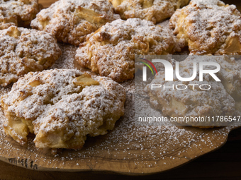 Close-up of artisanal apple and cinnamon cookies sprinkled with powdered sugar, arranged on a rustic olive wood board in City, Country, on N...