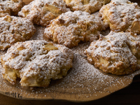 Close-up of artisanal apple and cinnamon cookies sprinkled with powdered sugar, arranged on a rustic olive wood board in City, Country, on N...