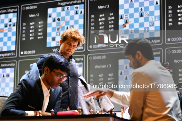 Indian GM Rameshbabu Praggnanandhaa (L) plays against Indian GM Vidit Gujrathi (R) while Norway's GM Magnus Carlsen looks on during the Blit...