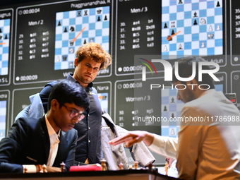 Indian GM Rameshbabu Praggnanandhaa (L) plays against Indian GM Vidit Gujrathi (R) while Norway's GM Magnus Carlsen looks on during the Blit...