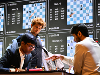 Indian GM Rameshbabu Praggnanandhaa (L) plays against Indian GM Vidit Gujrathi (R) while Norway's GM Magnus Carlsen looks on during the Blit...