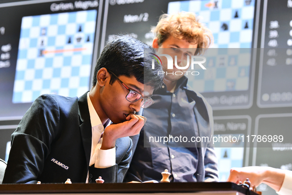 Indian GM Rameshbabu Praggnanandhaa plays against Indian GM Vidit Gujrathi (not visible in frame) while Norway's GM Magnus Carlsen observes...