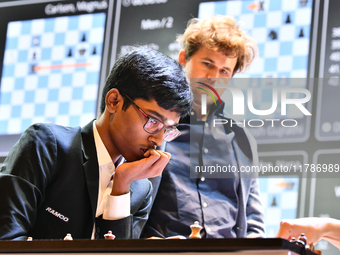 Indian GM Rameshbabu Praggnanandhaa plays against Indian GM Vidit Gujrathi (not visible in frame) while Norway's GM Magnus Carlsen observes...