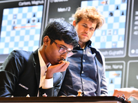 Indian GM Rameshbabu Praggnanandhaa plays against Indian GM Vidit Gujrathi (not visible in frame) while Norway's GM Magnus Carlsen observes...