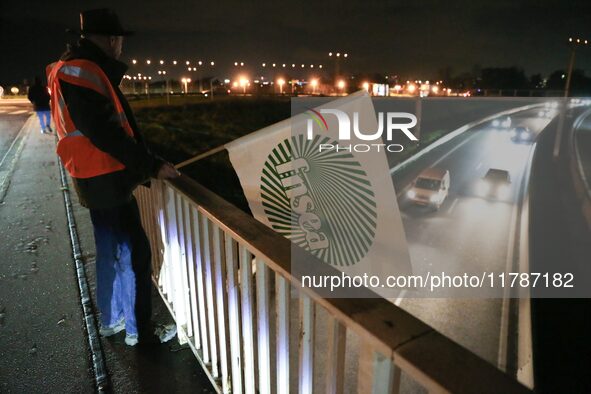 A farmer from the FNSEA (Federation Nationale des syndicats d'exploitants agricoles) union holds a flag on the RN118 road at the start of a...