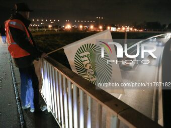 A farmer from the FNSEA (Federation Nationale des syndicats d'exploitants agricoles) union holds a flag on the RN118 road at the start of a...