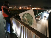 A farmer from the FNSEA (Federation Nationale des syndicats d'exploitants agricoles) union holds a flag on the RN118 road at the start of a...