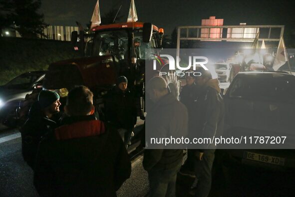 Farmers of the FNSEA (Federation Nationale des syndicats d'exploitants agricoles) union gather next to their tractors on the RN118 road at t...