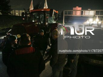 Farmers of the FNSEA (Federation Nationale des syndicats d'exploitants agricoles) union gather next to their tractors on the RN118 road at t...