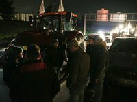 Farmers of the FNSEA (Federation Nationale des syndicats d'exploitants agricoles) union gather next to their tractors on the RN118 road at t...