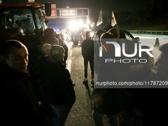 Farmers of the FNSEA (Federation Nationale des syndicats d'exploitants agricoles) union gather next to their tractors on the RN118 road at t...