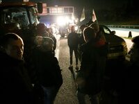 Farmers of the FNSEA (Federation Nationale des syndicats d'exploitants agricoles) union gather next to their tractors on the RN118 road at t...