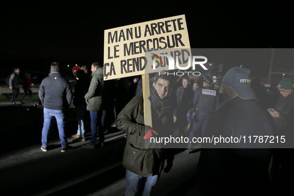 A farmer holds a placard with a play on words that reads, ''Manu, stop the Mercosur, it makes you deaf,'' on the RN118 road at the start of...