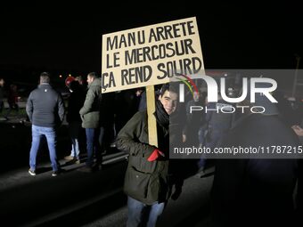 A farmer holds a placard with a play on words that reads, ''Manu, stop the Mercosur, it makes you deaf,'' on the RN118 road at the start of...