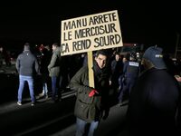 A farmer holds a placard with a play on words that reads, ''Manu, stop the Mercosur, it makes you deaf,'' on the RN118 road at the start of...