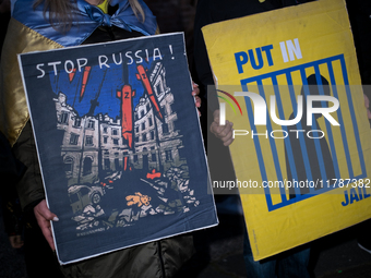 Protesters hold signs as they gather to participate in a demonstration marking the upcoming anniversary of 1,000 days since Russia's invasio...