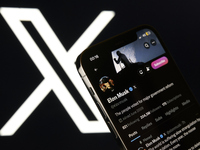 An editorial image shows an iPhone screen displaying Elon Musk’s personal account on the X social network platform. The X logo appears subtl...