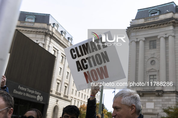 A climate protester holds a sign while environmental activists demonstrate outside the Federal Triangle Metro Station in Washington DC, USA,...