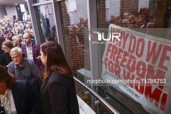 People hold a banner protesting outside a building during the opening of 'Manifesto' exhibition in the Centre Of Contemporary Art in Torun,...