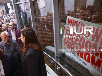 People hold a banner protesting outside a building during the opening of 'Manifesto' exhibition in the Centre Of Contemporary Art in Torun,...