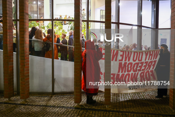 People hold a banner protesting outside a building during the opening of 'Manifesto' exhibition in the Centre Of Contemporary Art in Torun,...