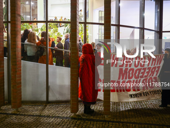 People hold a banner protesting outside a building during the opening of 'Manifesto' exhibition in the Centre Of Contemporary Art in Torun,...