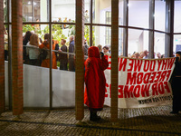 People hold a banner protesting outside a building during the opening of 'Manifesto' exhibition in the Centre Of Contemporary Art in Torun,...