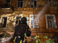 A firefighter sprays water during a response effort to a fire in a three-story residential building caused by a Russian missile and drone at...