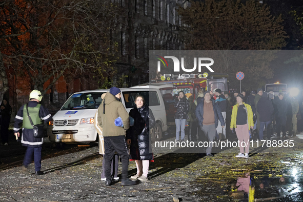 People watch a response effort to a fire in a three-story residential building caused by a Russian missile and drone attack in central Odesa...