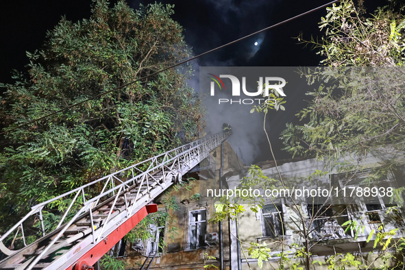 Firefighters climb a ladder to suppress a fire in a three-story residential building damaged by a Russian missile and drone attack in centra...