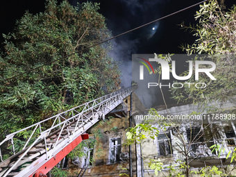 Firefighters climb a ladder to suppress a fire in a three-story residential building damaged by a Russian missile and drone attack in centra...