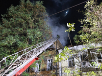 Firefighters climb a ladder to suppress a fire in a three-story residential building damaged by a Russian missile and drone attack in centra...