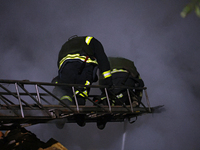 Firefighters climb a ladder to suppress a fire in a three-story residential building damaged by a Russian missile and drone attack in centra...