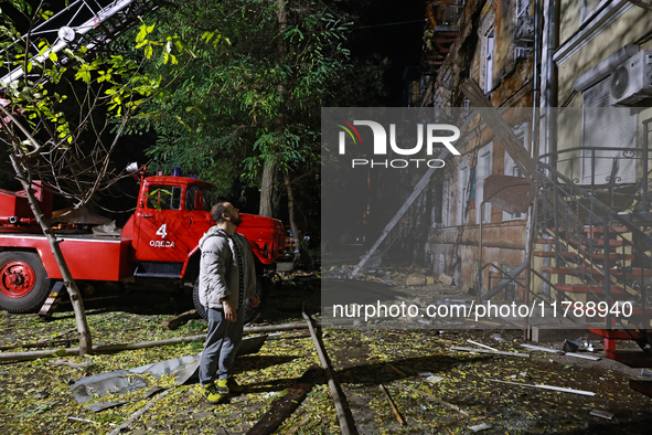 A man looks up during a response effort to a fire in a three-story residential building caused by a Russian missile and drone attack in cent...