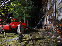 A man looks up during a response effort to a fire in a three-story residential building caused by a Russian missile and drone attack in cent...