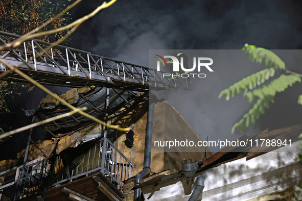 Firefighters climb a ladder to suppress a fire in a three-story residential building damaged by a Russian missile and drone attack in centra...