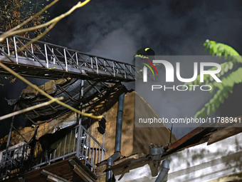 Firefighters climb a ladder to suppress a fire in a three-story residential building damaged by a Russian missile and drone attack in centra...