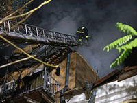 Firefighters climb a ladder to suppress a fire in a three-story residential building damaged by a Russian missile and drone attack in centra...