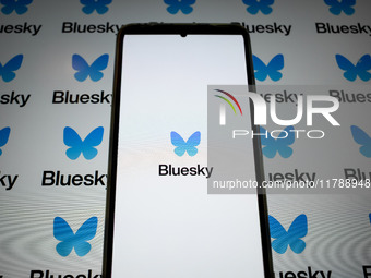 The Bluesky logo appears on a smartphone screen and as a background on a computer screen in this photo illustration in Athens, Greece, on No...