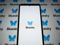 The Bluesky logo appears on a smartphone screen and as a background on a computer screen in this photo illustration in Athens, Greece, on No...