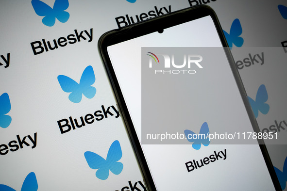 The Bluesky logo appears on a smartphone screen and as a background on a computer screen in this photo illustration in Athens, Greece, on No...