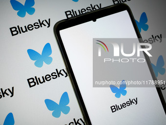 The Bluesky logo appears on a smartphone screen and as a background on a computer screen in this photo illustration in Athens, Greece, on No...