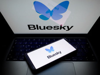 The Bluesky logo appears on a smartphone screen and as a background on a computer screen in this photo illustration in Athens, Greece, on No...