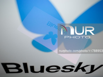 The Bluesky logo appears on a smartphone screen and as a background on a computer screen in this photo illustration in Athens, Greece, on No...